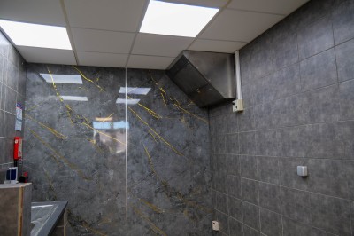 Salle de bain moderne avec lavabo, miroir rond, toilettes et urinoir, murs en marbre et sol carrelé.