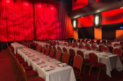 Miniature La Grande Salle - Format banquet Salle de réunion avec table rectangulaire noire, chaises rouges, murs en bois strié et écran mural.