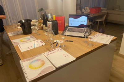 Bouteille de vin blanc, verres, assiette de carpaccio et documents de dégustation sur une table dressée.