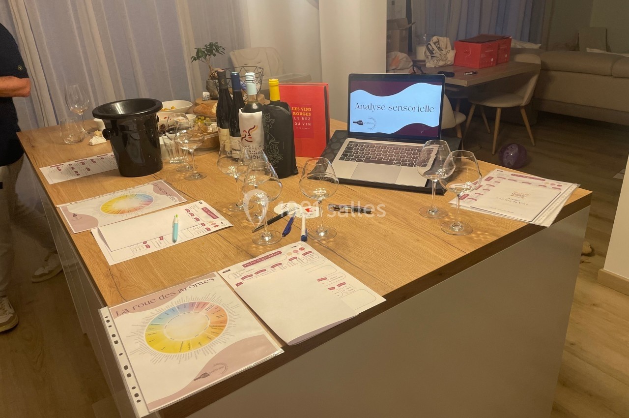 Table en bois avec verres à vin, documents d'analyse sensorielle, bouteilles et ordinateur affichant une présentation.