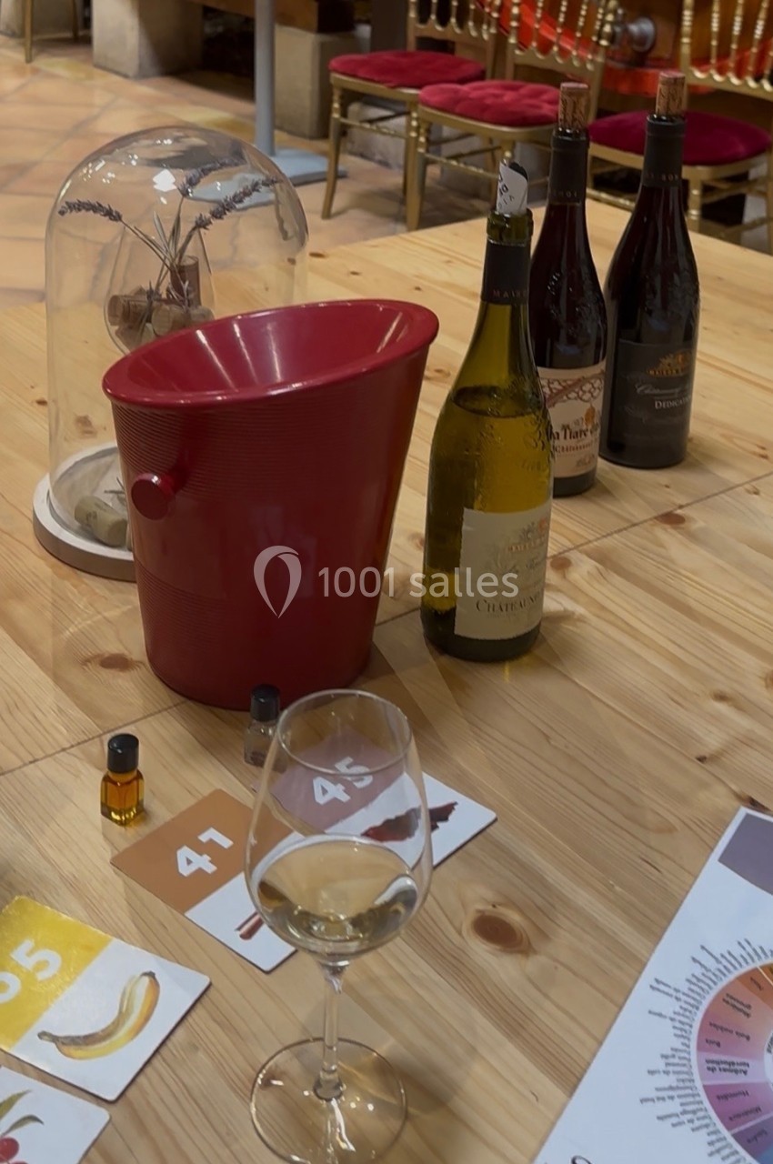 Verres, bouteilles de vin, seau rouge et supports d'arômes sur une table en bois dans un cadre de dégustation.