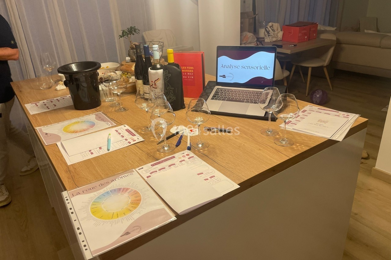 Table en bois avec verres, bouteilles de vin, documents d'analyse sensorielle et ordinateur affichant une présentation.