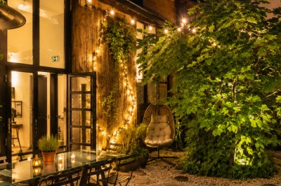Espace de détente avec bancs et tables en bois, décor alpin avec montagnes en arrière-plan et éclairage chaleureux.