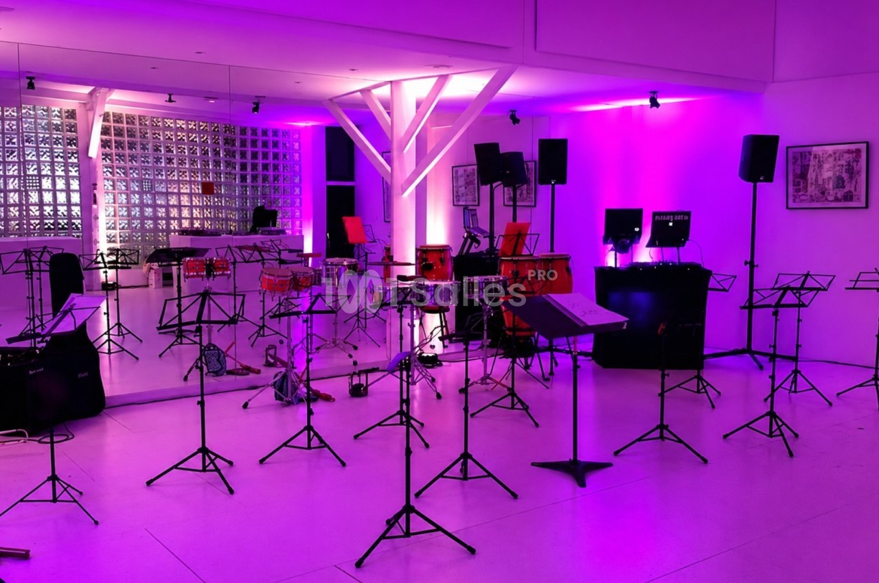 Salle de répétition avec des pupitres, instruments de musique et éclairage violet.