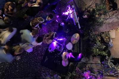 Grande table en bois dressée avec vaisselle, bougies et décorations, dans une salle au mur de briques et sol en terre cuite.