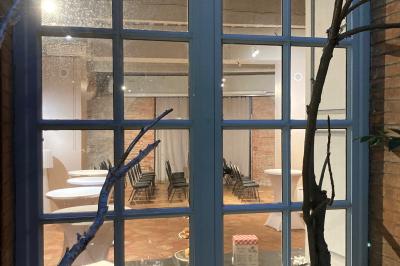 Grande table en bois dressée avec vaisselle, bougies et décorations, dans une salle au mur de briques et sol en terre cuite.