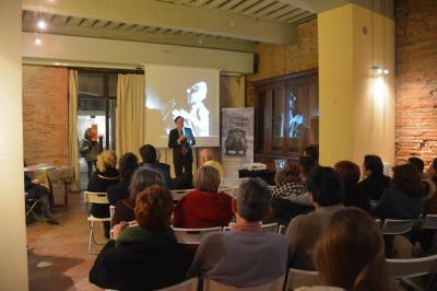 Grande table en bois dressée avec vaisselle, bougies et décorations, dans une salle au mur de briques et sol en terre cuite.