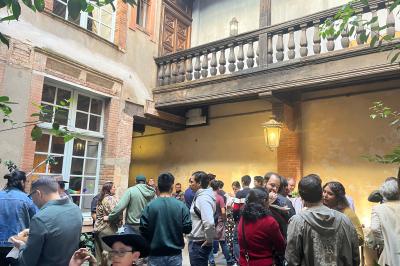 Grande table en bois dressée avec vaisselle, bougies et décorations, dans une salle au mur de briques et sol en terre cuite.