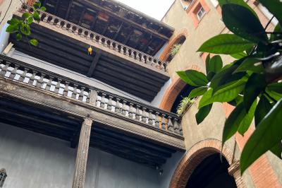 Grande table en bois dressée avec vaisselle, bougies et décorations, dans une salle au mur de briques et sol en terre cuite.