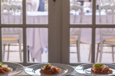 Grande table en bois dressée avec vaisselle, bougies et décorations, dans une salle au mur de briques et sol en terre cuite.