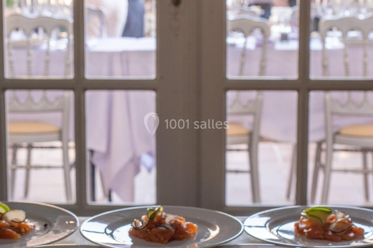 Assiettes de saumon fumé garnies de légumes, disposées sur une table devant une porte vitrée donnant sur une réception.