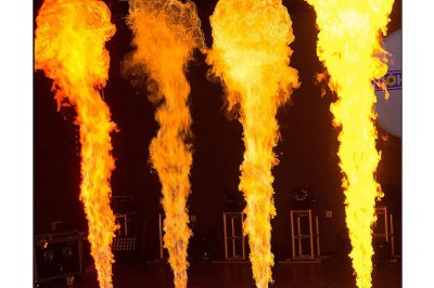 Miniature Artifice & Sfx Corporation #3 Jets de flammes verticales de différentes intensités émanant de dispositifs au sol dans une salle sombre.