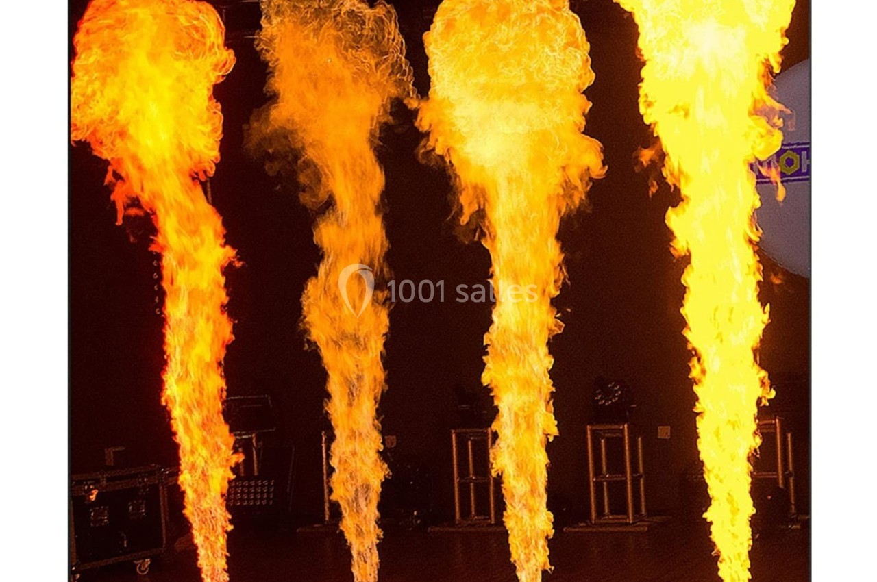 Jets de flammes verticales de différentes intensités émanant de dispositifs au sol dans une salle sombre.