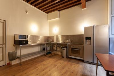 Cour intérieure pavée avec des plantes en pots, entourée de murs en briques et fenêtres à carreaux.