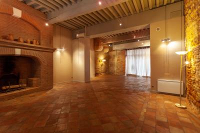 Cour intérieure pavée avec des plantes en pots, entourée de murs en briques et fenêtres à carreaux.