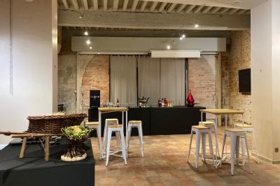 Cour intérieure pavée avec des plantes en pots, entourée de murs en briques et fenêtres à carreaux.