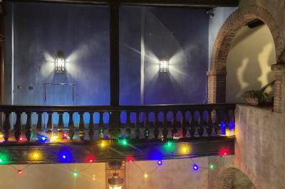 Cour intérieure pavée avec des plantes en pots, entourée de murs en briques et fenêtres à carreaux.