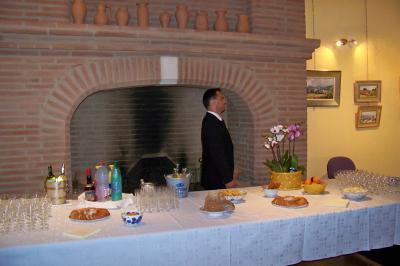 Cour intérieure pavée avec des plantes en pots, entourée de murs en briques et fenêtres à carreaux.