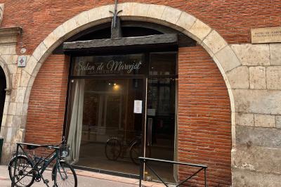 Cour intérieure pavée avec des plantes en pots, entourée de murs en briques et fenêtres à carreaux.