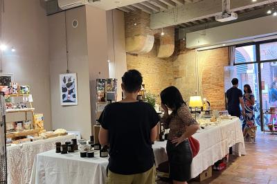 Cour intérieure pavée avec des plantes en pots, entourée de murs en briques et fenêtres à carreaux.