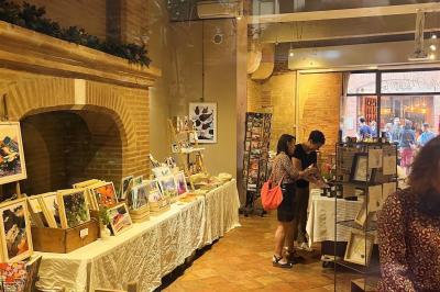 Cour intérieure pavée avec des plantes en pots, entourée de murs en briques et fenêtres à carreaux.