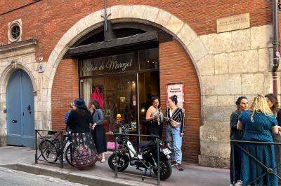 Cour intérieure pavée avec des plantes en pots, entourée de murs en briques et fenêtres à carreaux.