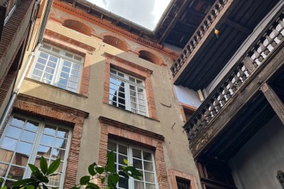 Télévision murale sur un mur de briques, table en bois avec des plantes en pots et un bouquet de fleurs colorées.