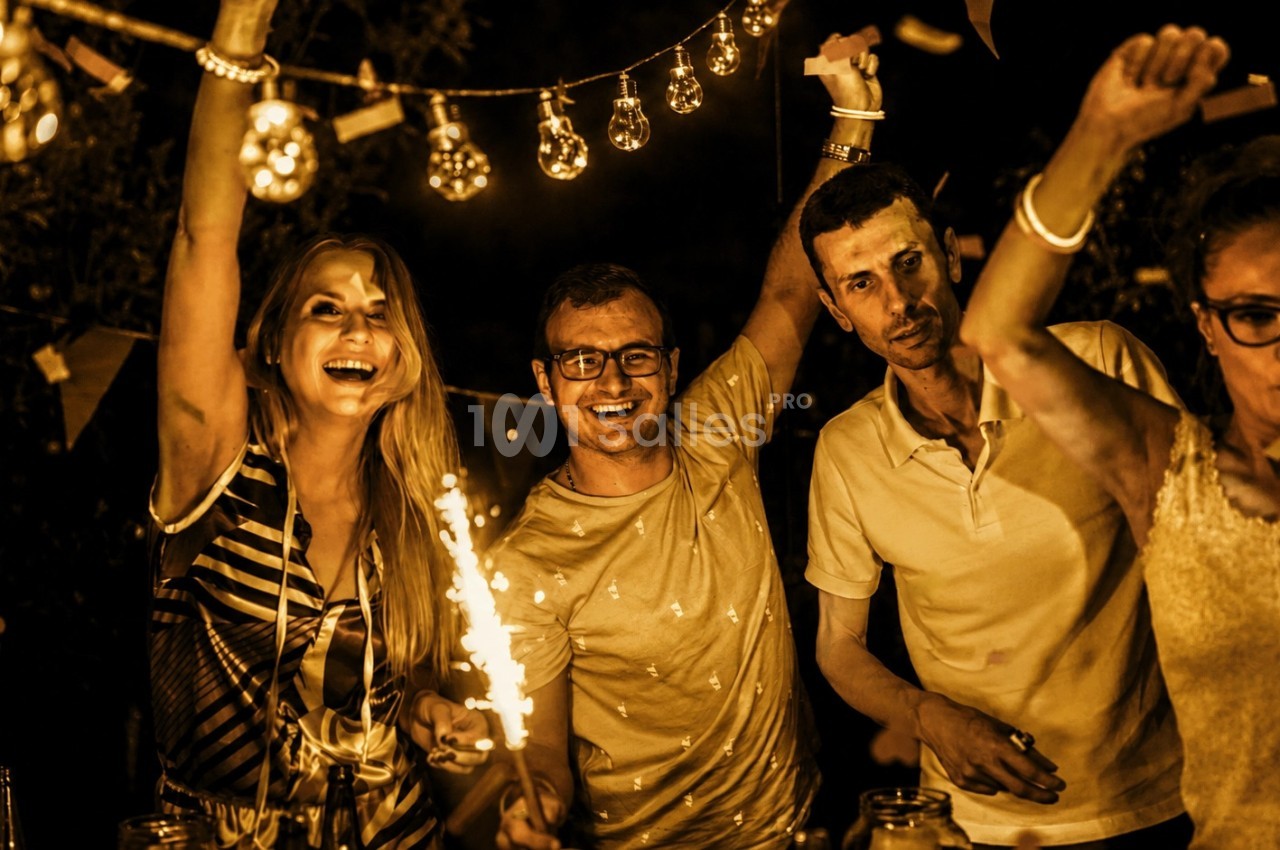 Convives dansant en extérieur sous des guirlandes lumineuses, atmosphère festive nocturne.