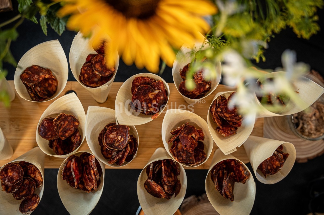 Amuse-bouches de viande en croûte servies dans des cuillères en bois, décoration florale jaune en arrière-plan.