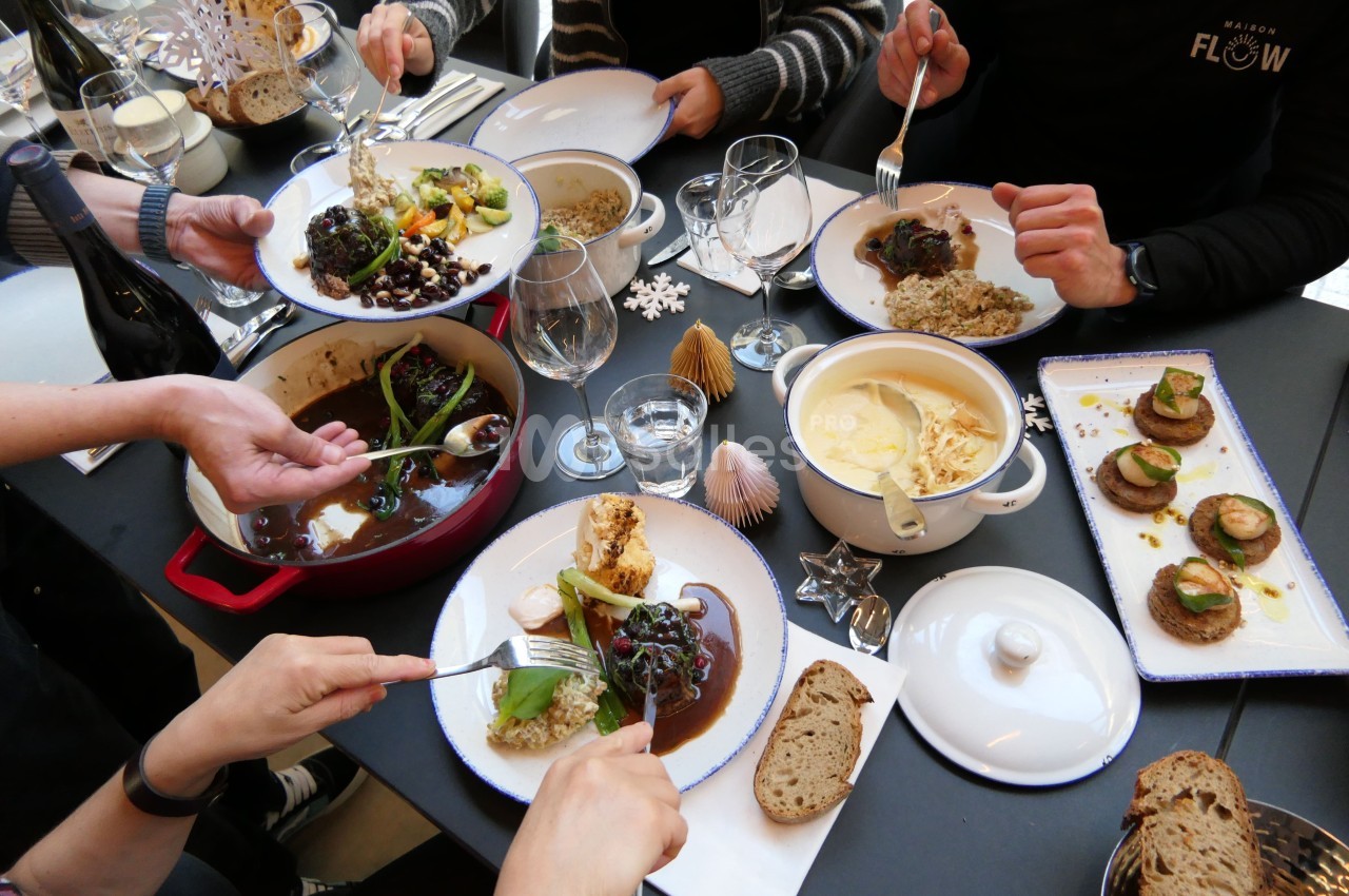 Tablée de convives servant des plats dressés sur assiettes et dans des cocottes : viande en sauce, légumes, risotto, petites bouchées de tartare de poisson au pain, et du pain sur la table. Let me check length: roughly 170 characters, too long. Need