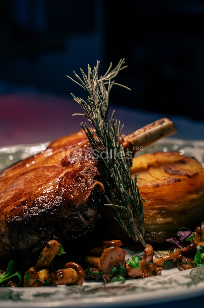Côte de boeuf rôtie garnie de romarin frais, accompagnée de champignons et légumes de saison.