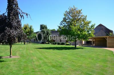 Salle de réception décorée avec des tables dressées, des guirlandes lumineuses et des voilages suspendus au plafond.