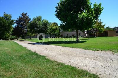 Salle de réception décorée avec des tables dressées, des guirlandes lumineuses et des voilages suspendus au plafond.