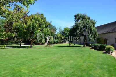 Salle de réception décorée avec des tables dressées, des guirlandes lumineuses et des voilages suspendus au plafond.