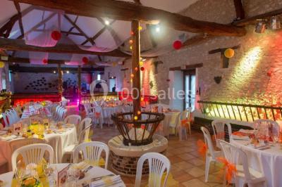 Salle de réception décorée avec des tables dressées, des guirlandes lumineuses et des voilages suspendus au plafond.