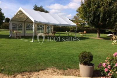 Salle de réception décorée avec des tables dressées, des guirlandes lumineuses et des voilages suspendus au plafond.