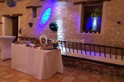 Salle de réception décorée avec des tables dressées, des guirlandes lumineuses et des voilages suspendus au plafond.