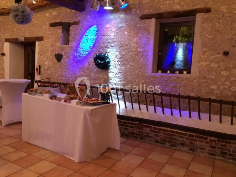 Table de buffet dressée dans une salle en pierre avec éclairage coloré et banc en bois le long du mur.