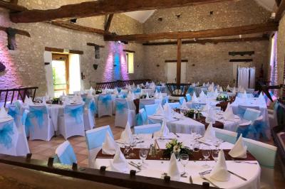 Salle de réception décorée avec des tables dressées, des guirlandes lumineuses et des voilages suspendus au plafond.
