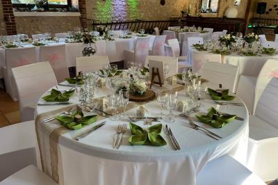Salle de réception décorée avec des tables dressées, des guirlandes lumineuses et des voilages suspendus au plafond.