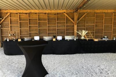 Salle de réception décorée avec des tables dressées, des guirlandes lumineuses et des voilages suspendus au plafond.