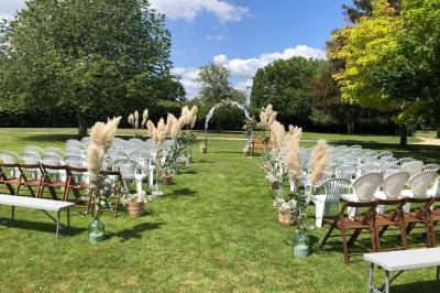 Salle de réception décorée avec des tables dressées, des guirlandes lumineuses et des voilages suspendus au plafond.