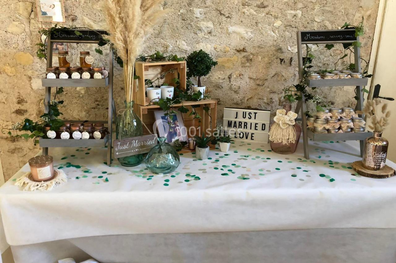 Table décorée pour un mariage avec pots de confiture, plantes, pancarte ’Just Married Love’ et éléments rustiques.