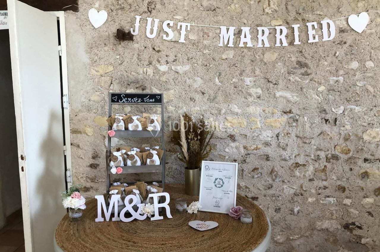 Décoration de mariage avec une table ornée de cadeaux d'invités, fleurs séchées et une bannière ’Just Married’.