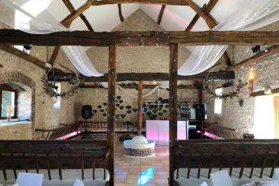 Salle de réception décorée avec des tables dressées, des guirlandes lumineuses et des voilages suspendus au plafond.