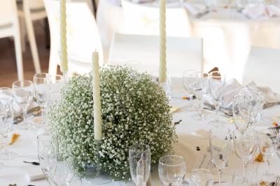 Salle de réception décorée avec des tables dressées, des guirlandes lumineuses et des voilages suspendus au plafond.