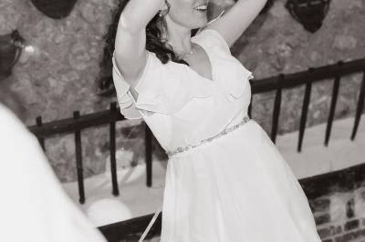 Salle de réception décorée avec des tables dressées, des guirlandes lumineuses et des voilages suspendus au plafond.