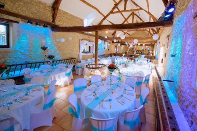 Salle de réception décorée avec des tables dressées, des guirlandes lumineuses et des voilages suspendus au plafond.