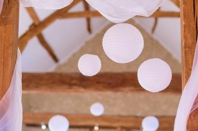 Salle de réception décorée avec des tables dressées, des guirlandes lumineuses et des voilages suspendus au plafond.