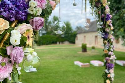 Salle de réception décorée avec des tables dressées, des guirlandes lumineuses et des voilages suspendus au plafond.